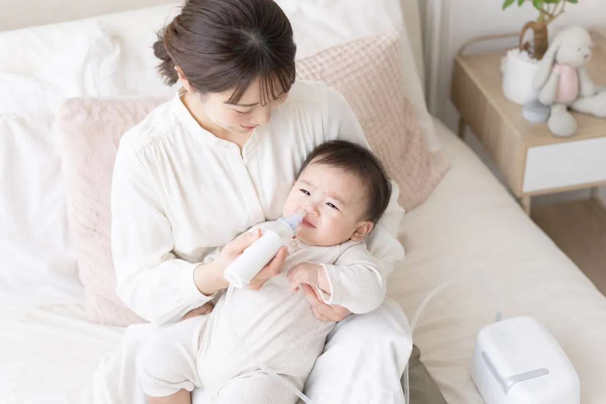 電動鼻水吸引器で赤ちゃんの鼻水を吸うママ