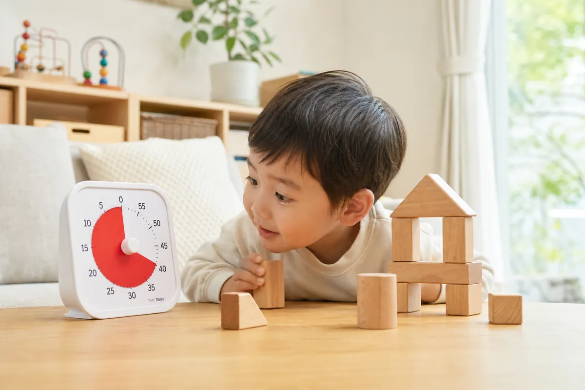 残り時間が色で減るタイマーをのぞき込む子ども
