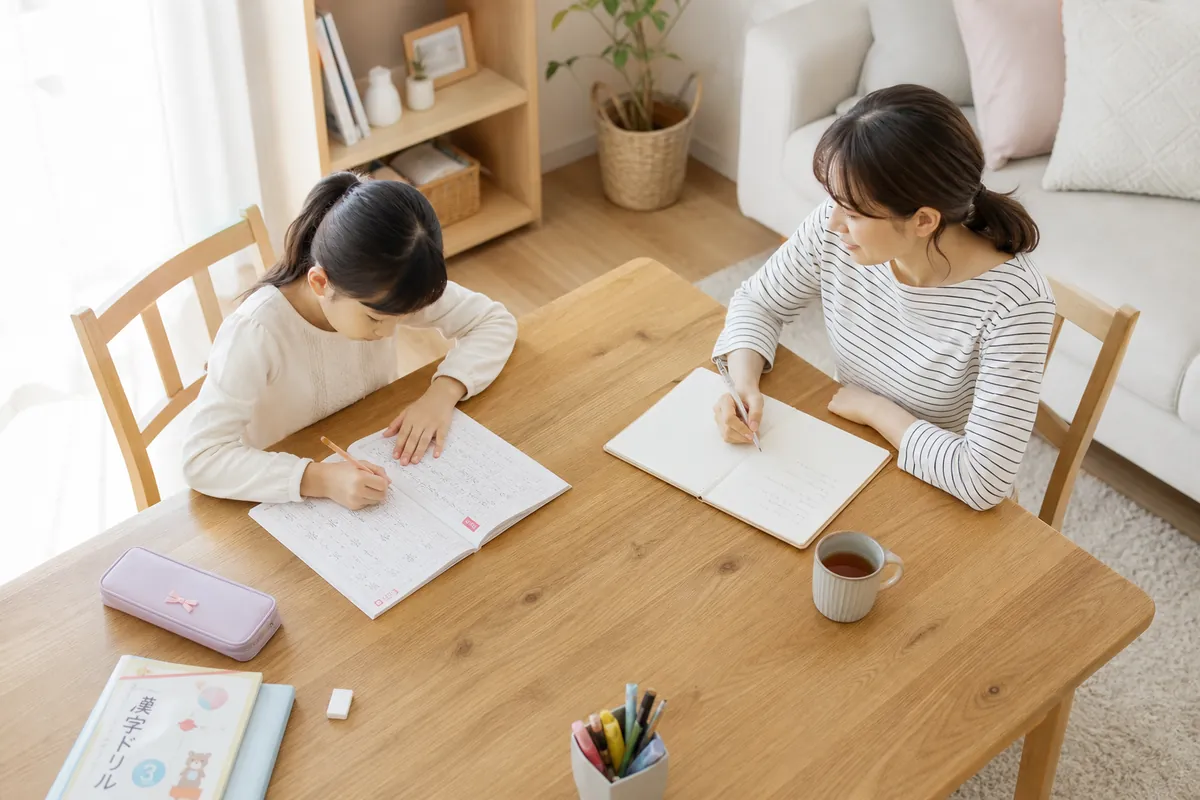 宿題をする女の子をそばで見守るママ
