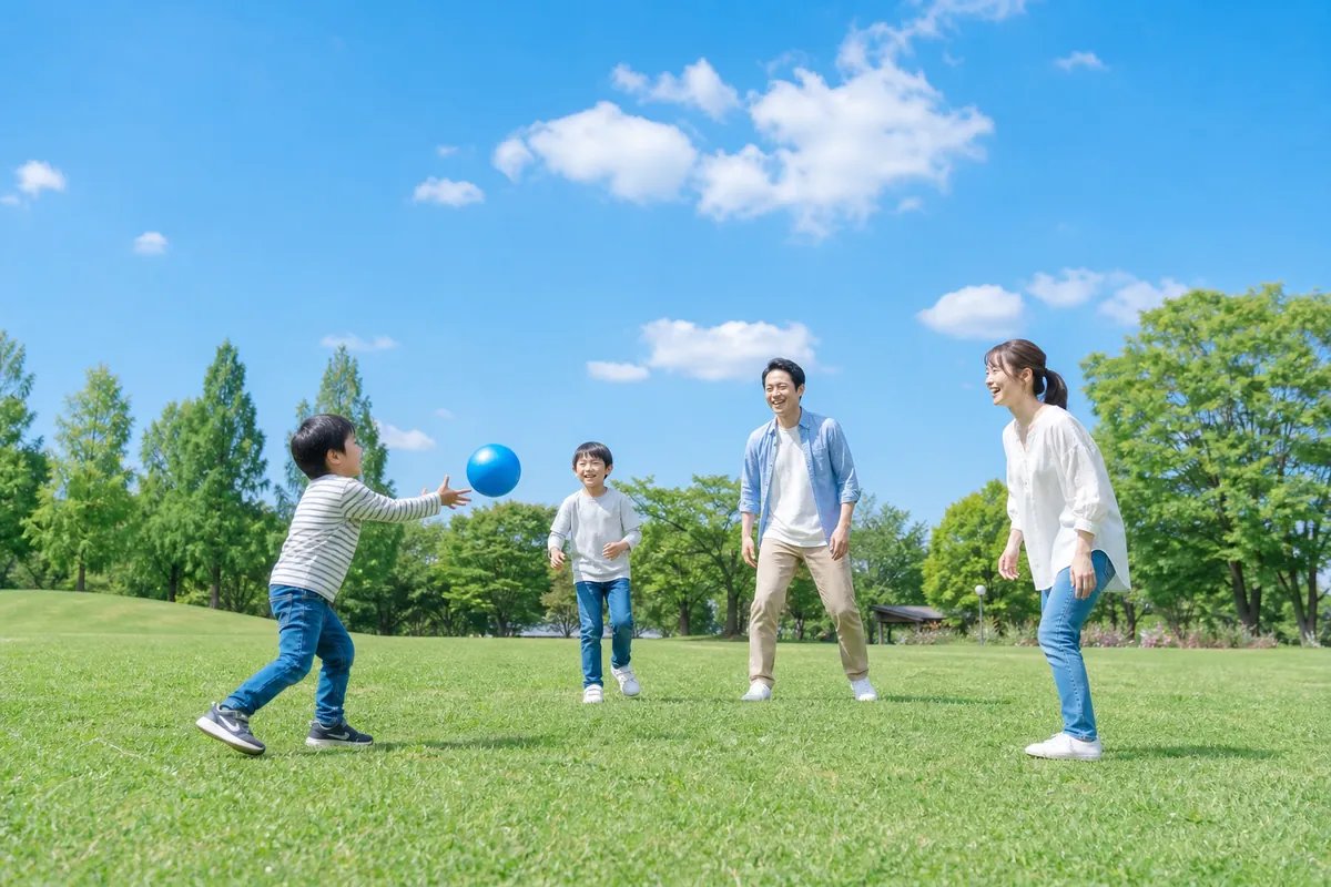 公園でボール遊びをする家族