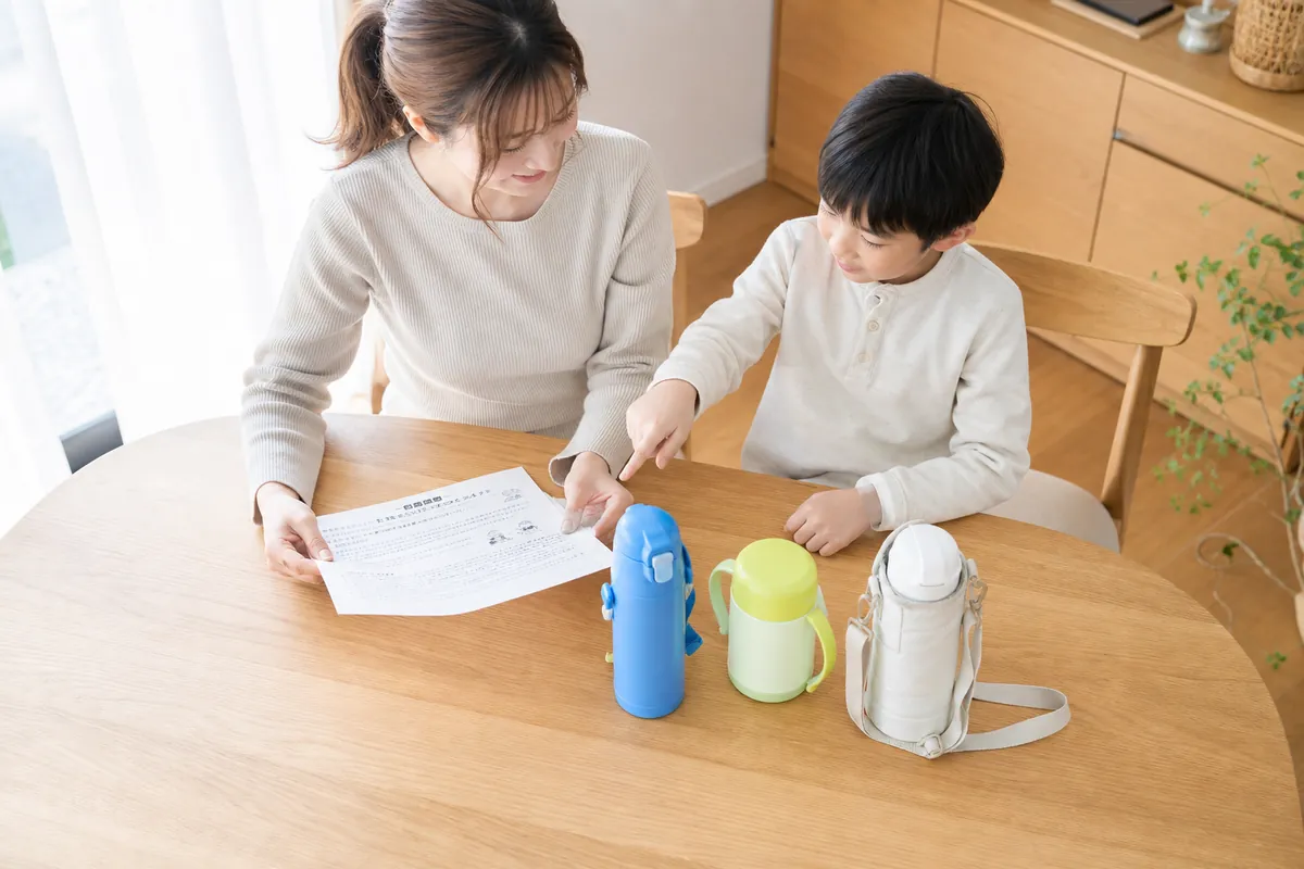 学校のお便りを見ながら水筒を選ぶ親子