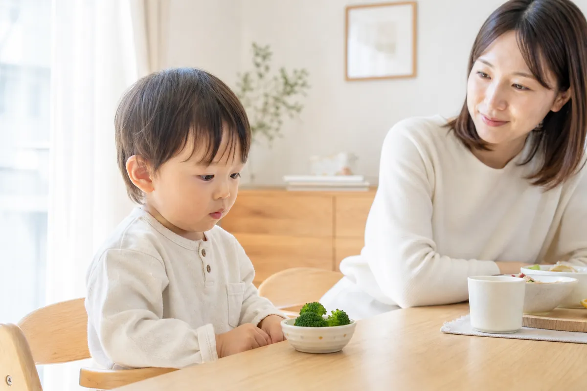 器のブロッコリーをじっと見つめる子どもと見守るママ