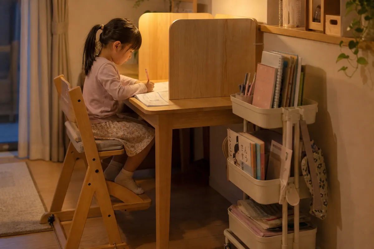 ダイニングテーブルに仕切りと収納ワゴンを足して勉強する小学生