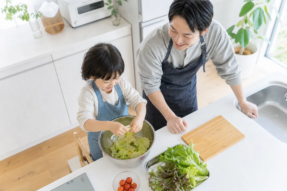 キッチンでレタスをちぎってお手伝いする子ども